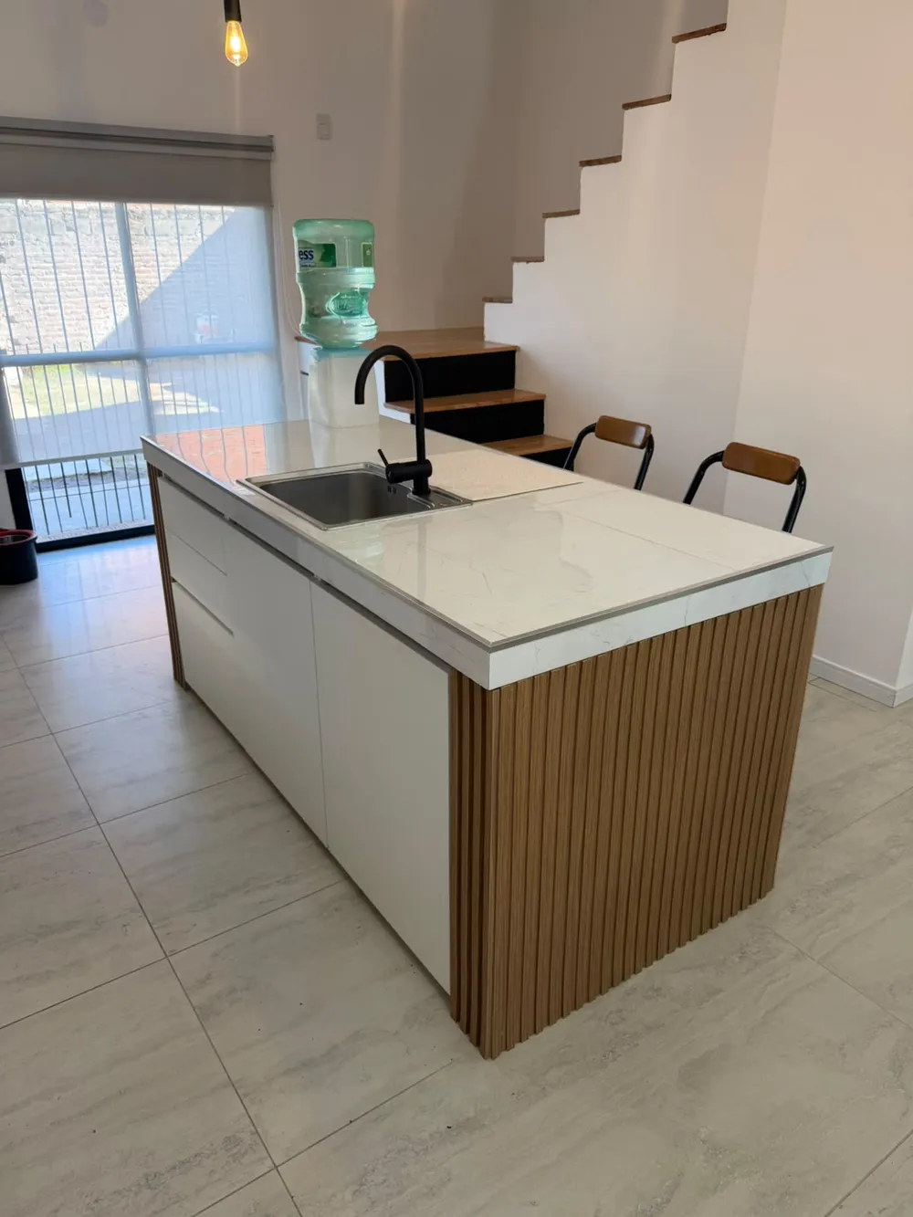 Isla de cocina con listones de madera vista de costado, junto a la escalera